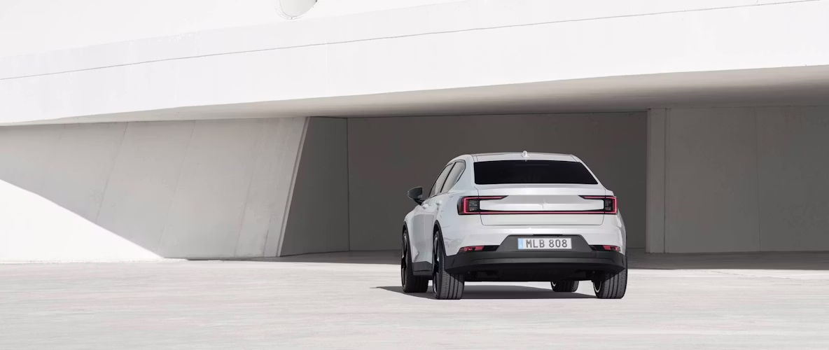 Polestar 2 di colore Snow, visto da dietro davanti a un edificio.