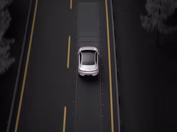 A top down view of Polestar 4 in Snow colour driving on a motorway with yellow lane markings