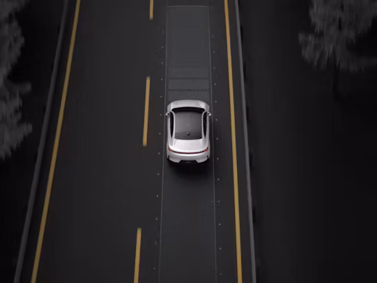 A top down view of Polestar 4 in Snow colour driving on a motorway with yellow lane markings