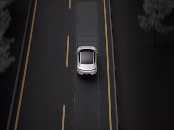 A top down view of Polestar 4 in Snow colour driving on a motorway with yellow lane markings