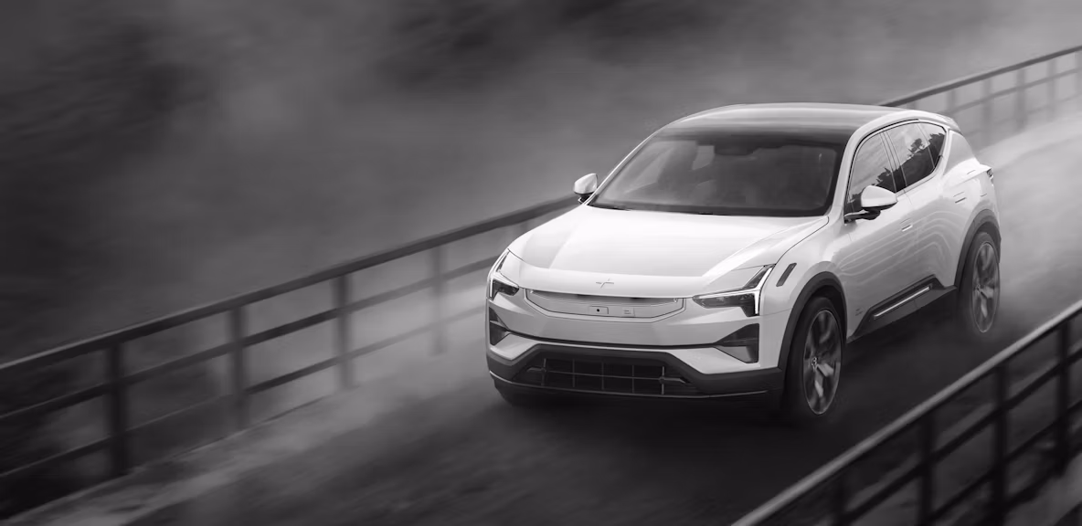 A white Polestar 3 driving on a bridge with a black and white coloured background.