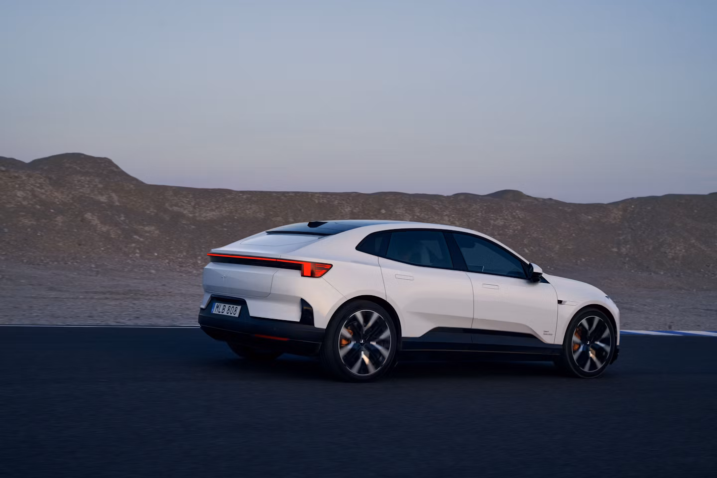 Polestar 4 rijdt op een circuit met berglandschap op de achtergrond.