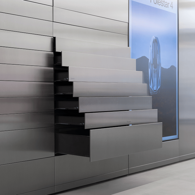 Metallic drawers extended from a wall next to a screen displaying Polestar 4 text and an abstract design.