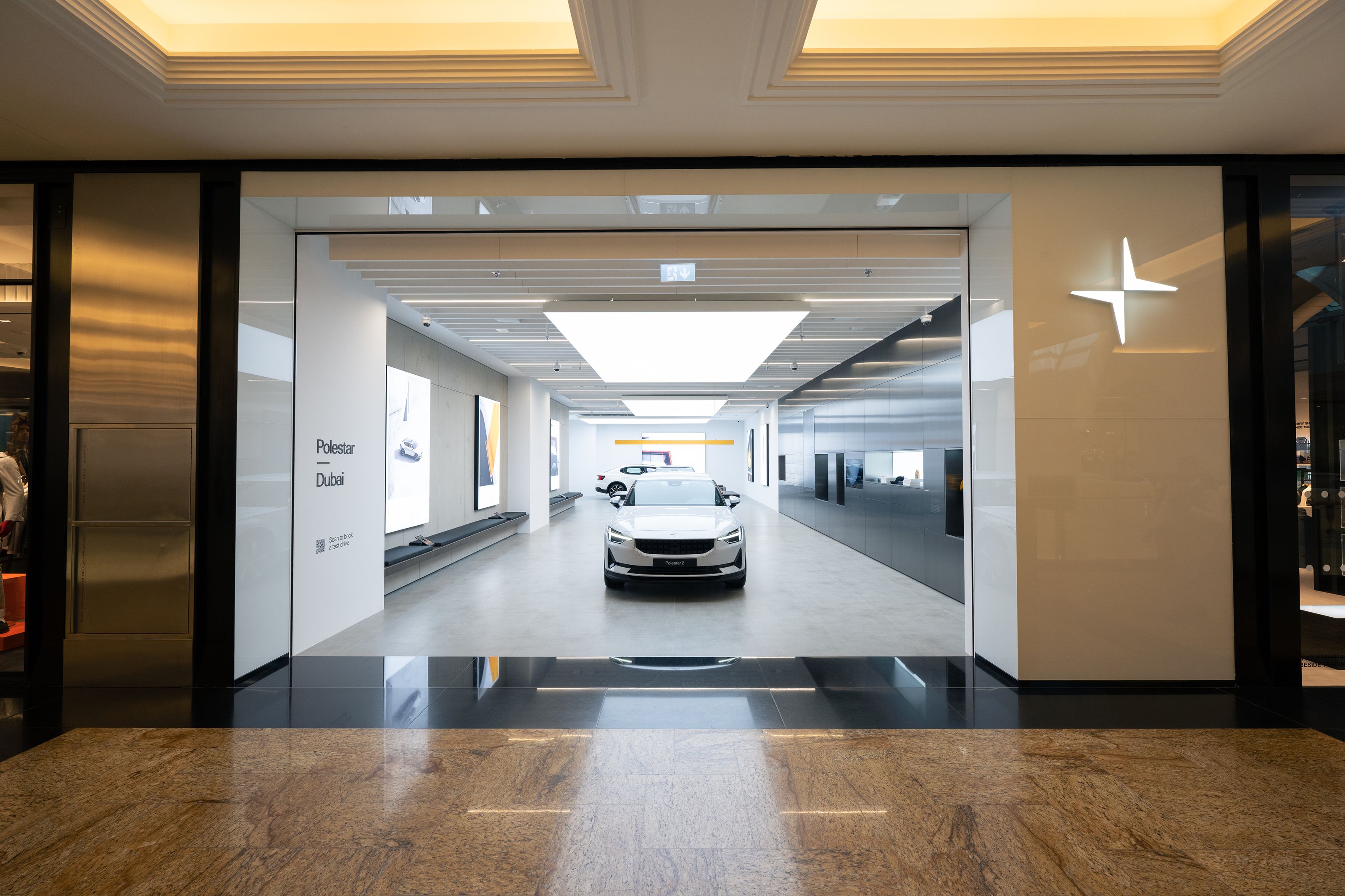 Polestar car displayed in a showroom with bright lighting and modern design, Polestar logo visible on the right wall.