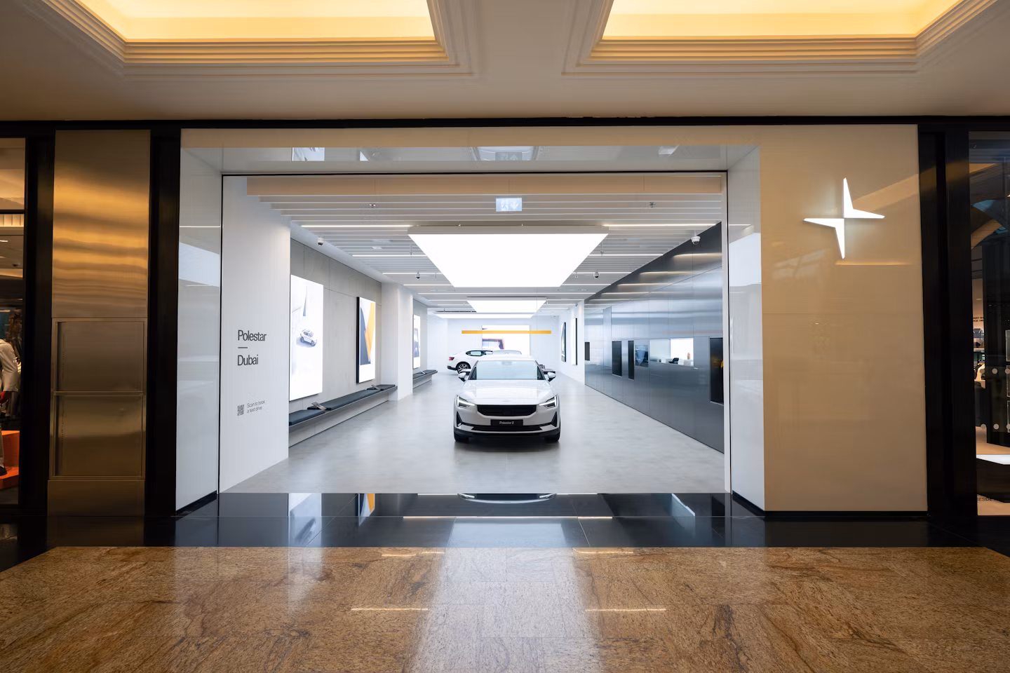 Polestar car displayed in a showroom with bright lighting and modern design, Polestar logo visible on the right wall.