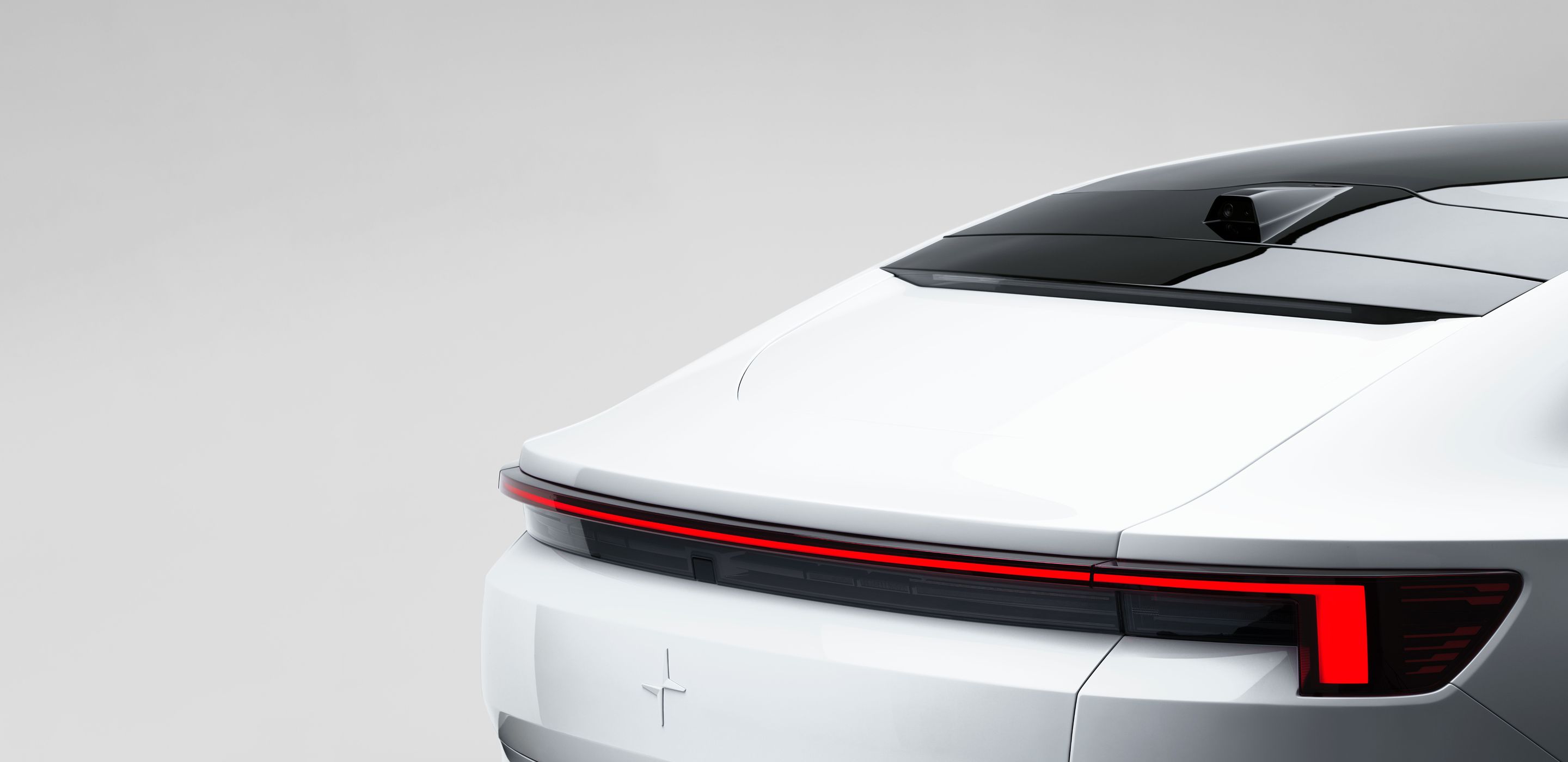 Rear view of Polestar 4 with red tail lights and black roof detail.