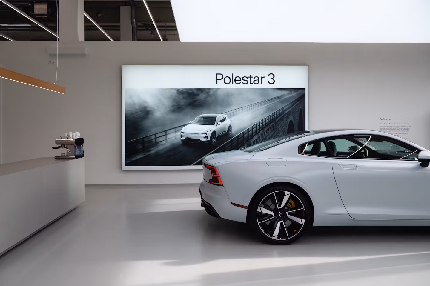 Polestar 3 vanaf zijaanzicht in een showroom met grote visual op de achtergrond.