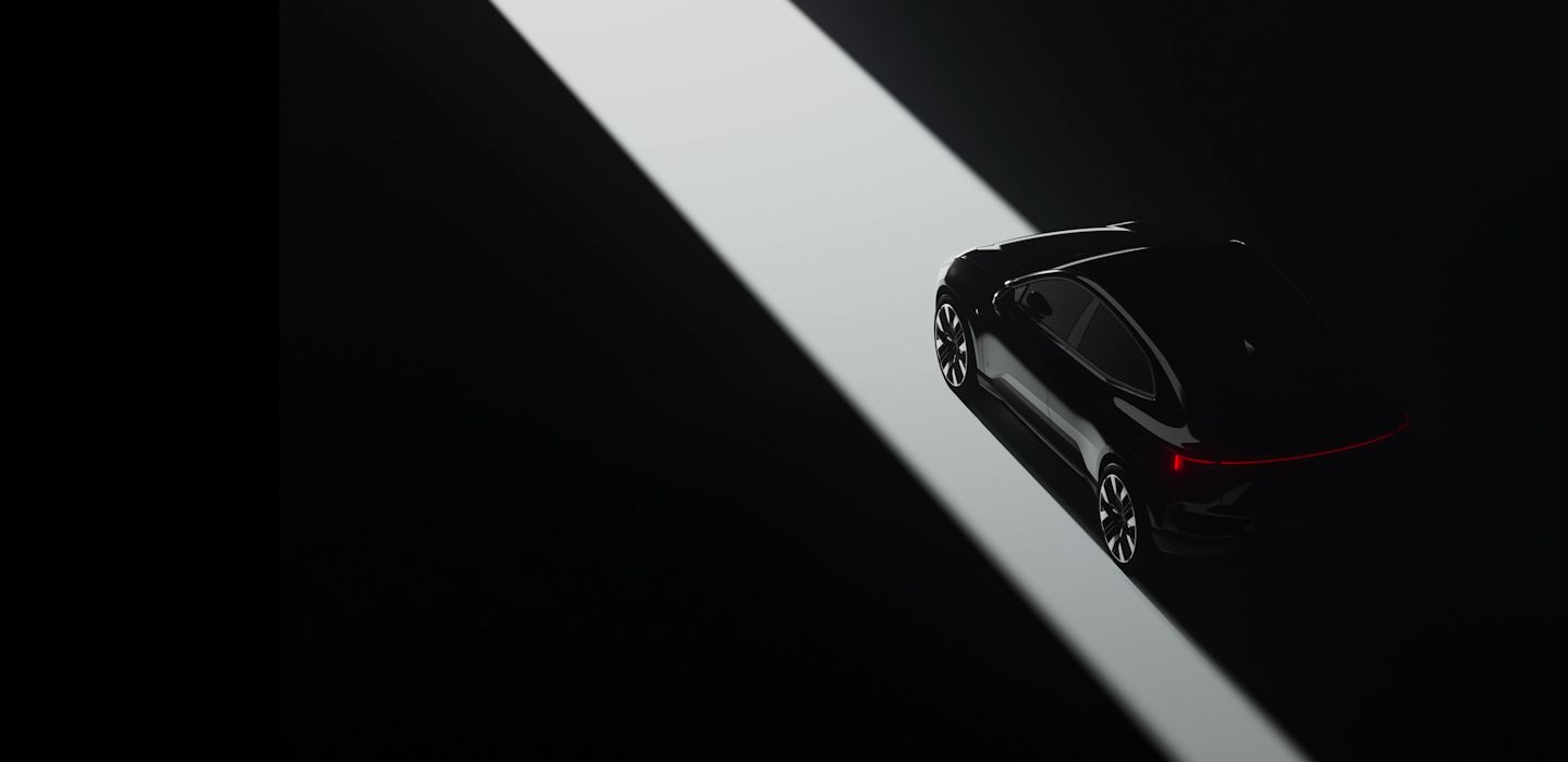 Polestar 4 car in dark setting with rear lights illuminated, positioned in a beam of light on a black background.