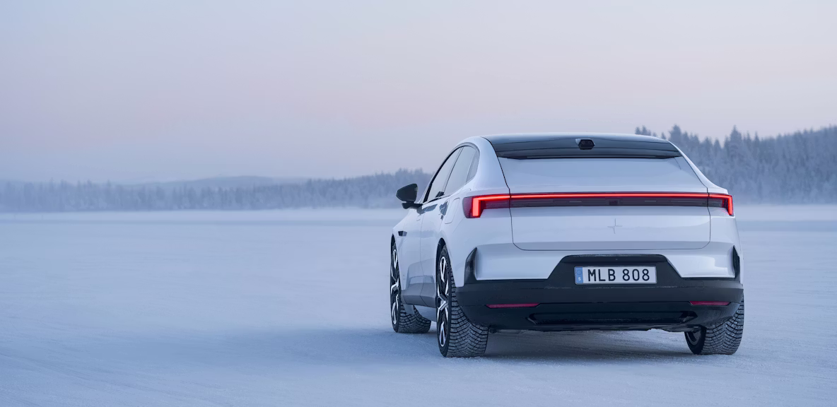 Polestar 4 car on snowy terrain with trees in the background under a pale sky.