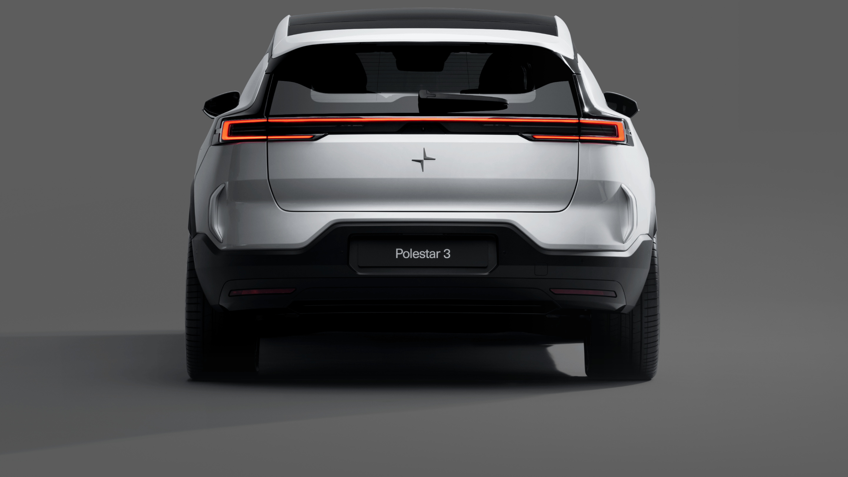A rear view of a white Polestar 3 standing against a grey background.