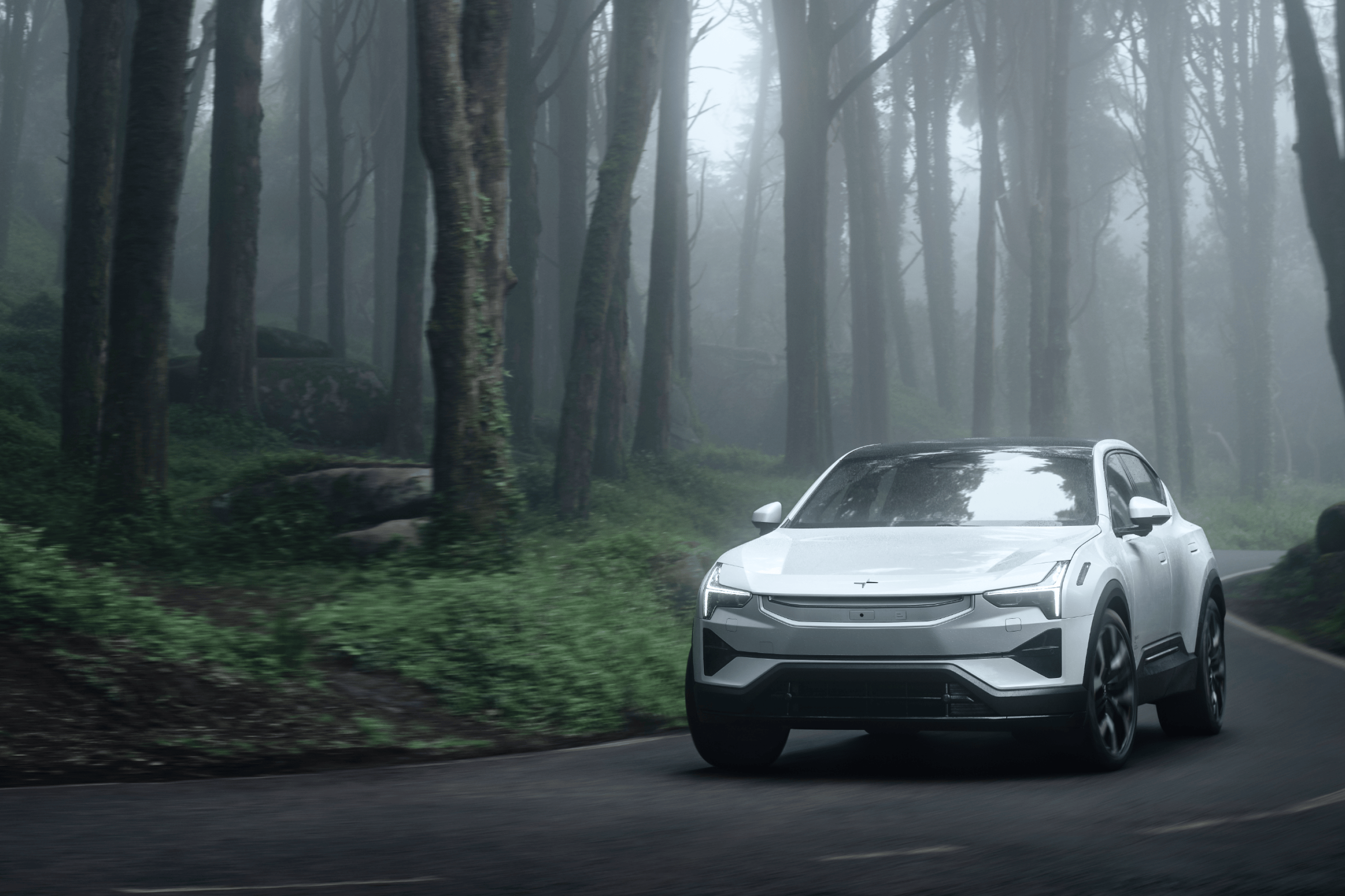 A white Polestar 3 driving on a road in a foggy environment with trees and green foliage.