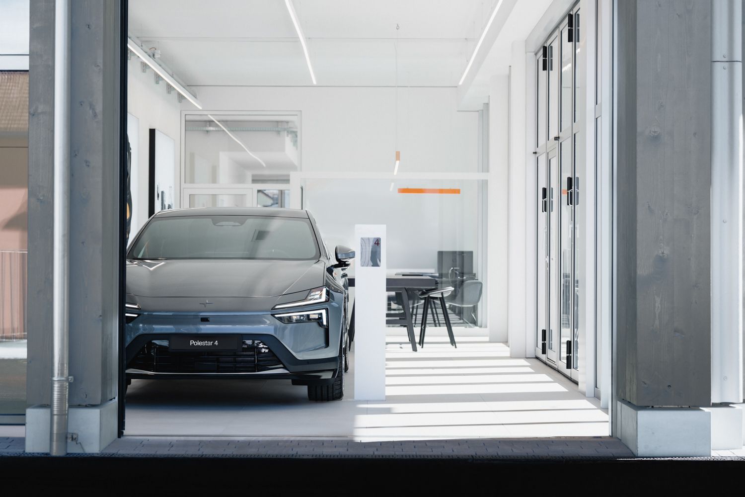 Innenansicht des Polestar Space in Oberuzwil mit einem Polestar 4 in der Farbe Storm von vorne.