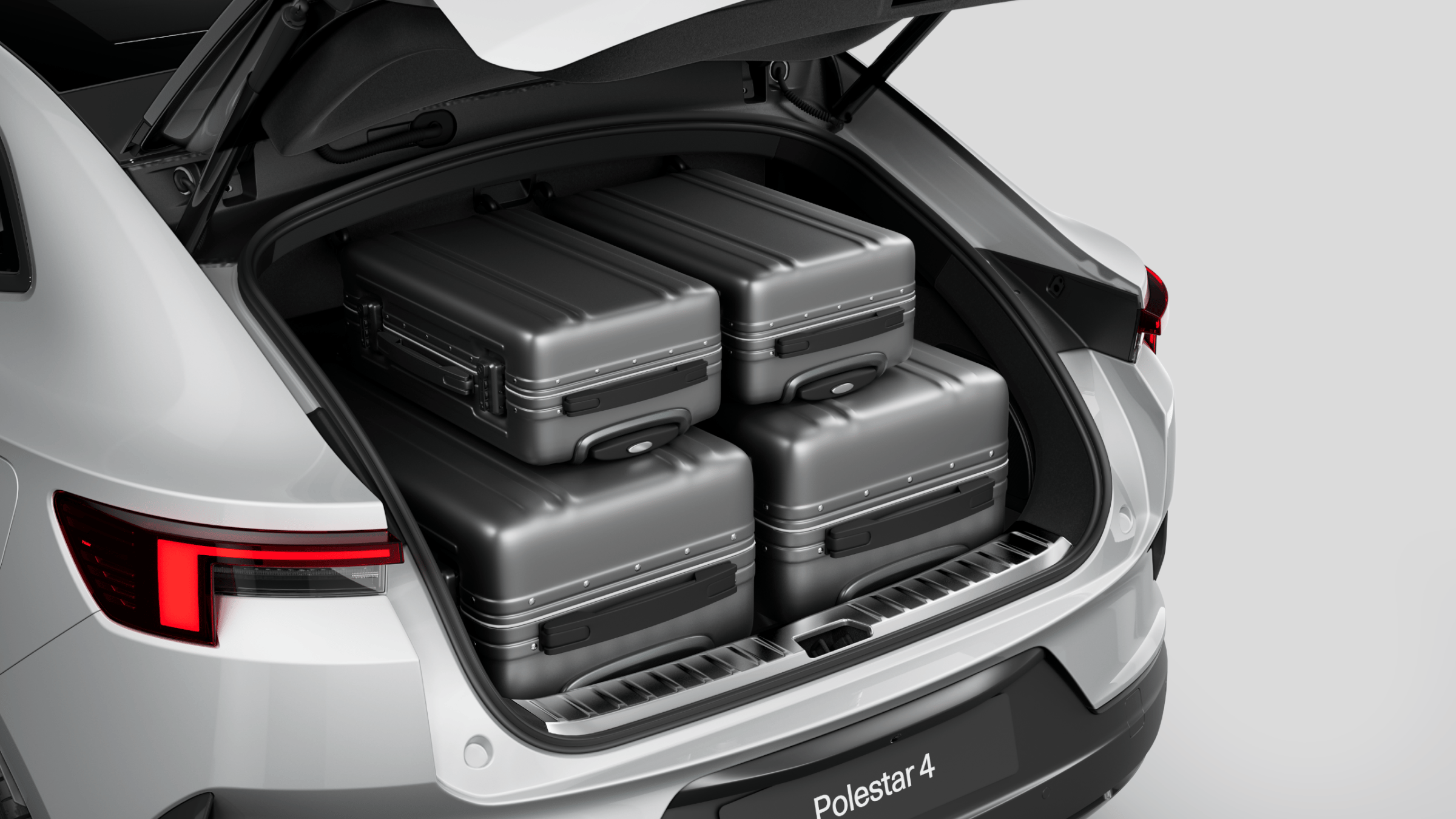 Polestar 4 coupé’s rear luggage compartment with two full-sized suitcases and smaller suitcases.