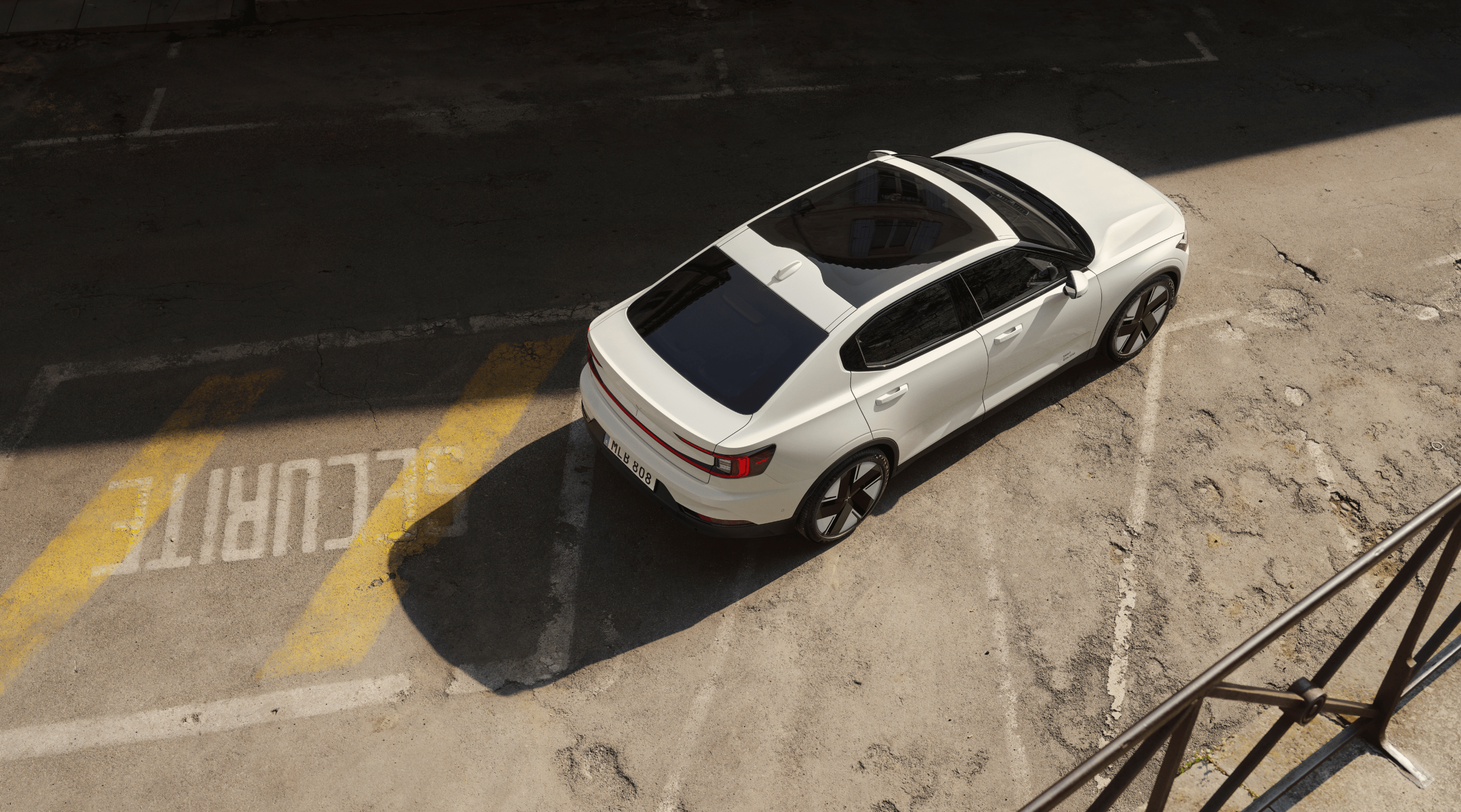 Polestar 2 standing on a parking lot with foreign lettering and worn out markings.