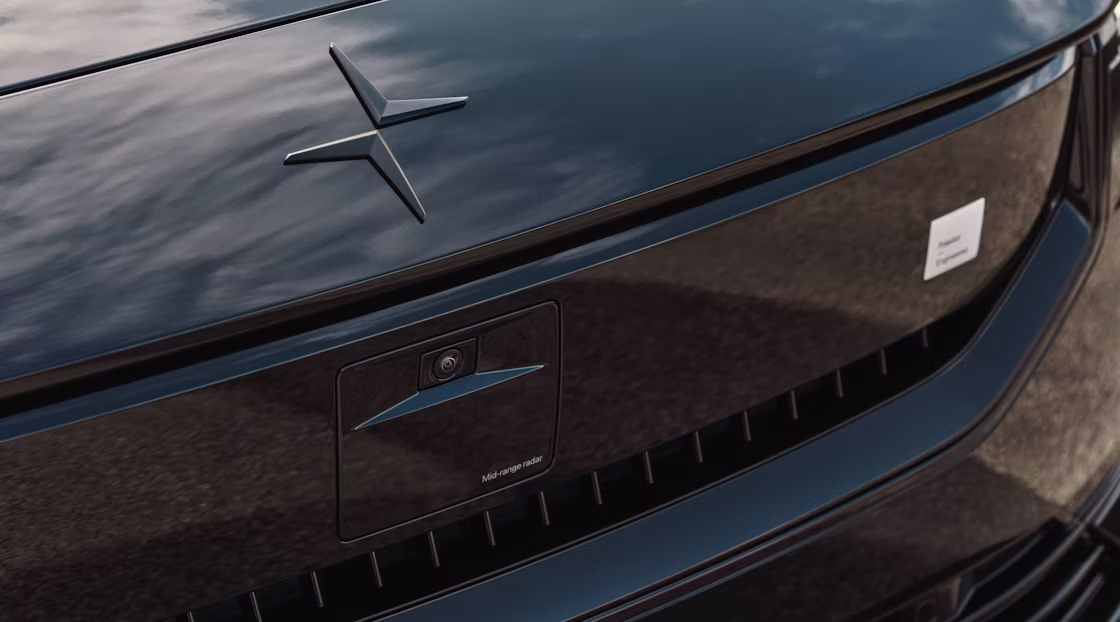 Close-up of Polestar 2’s hood with Polestar logo and smartzone with the sky reflected on surface.