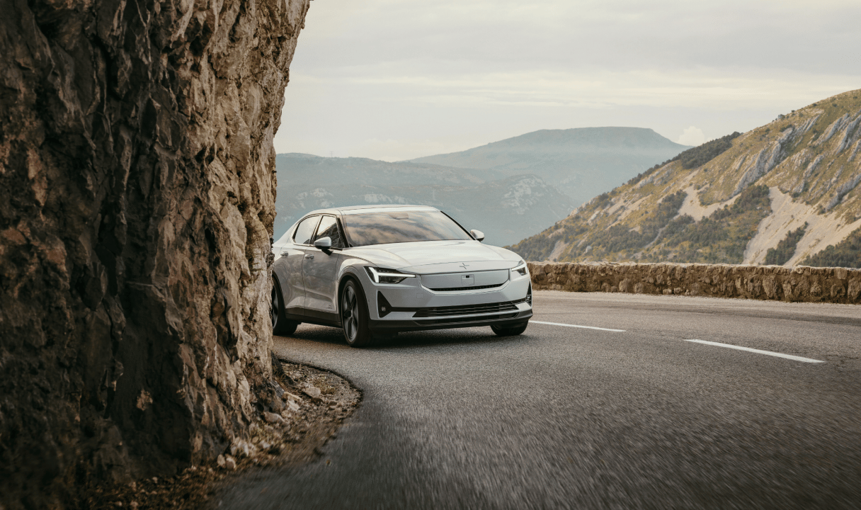 Polestar 2 on a mountain road beside a rock cliff