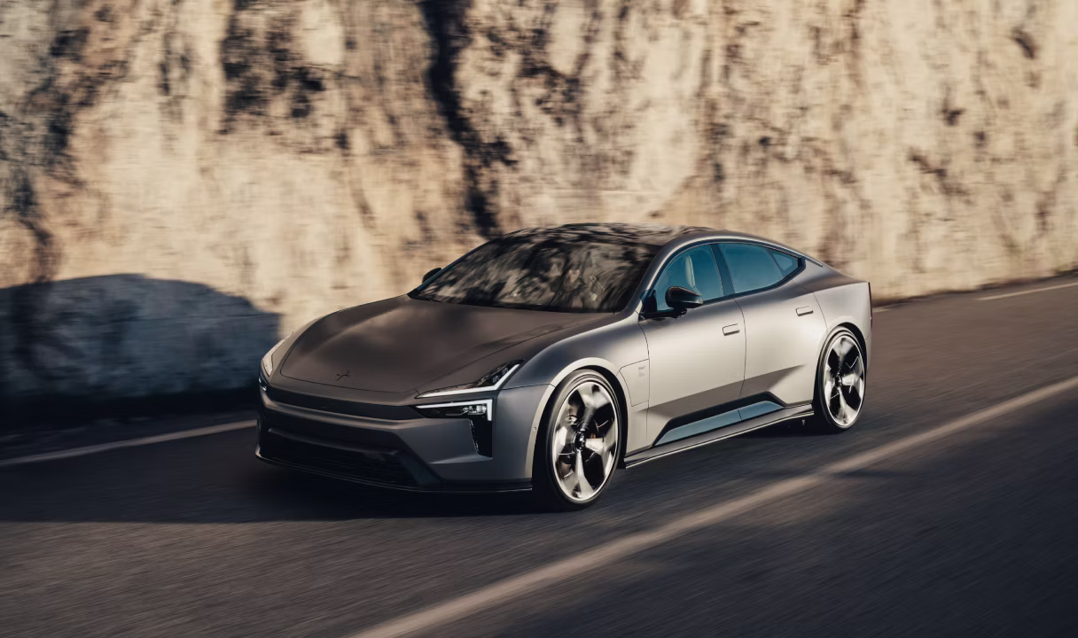 Polestar 5 driving on a road beside a rock wall