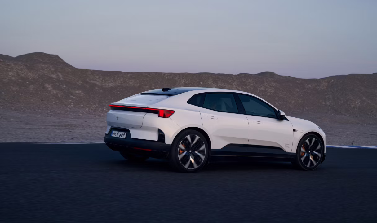 Polestar 4 Coupé driving on a road beside rocky hills at dusk