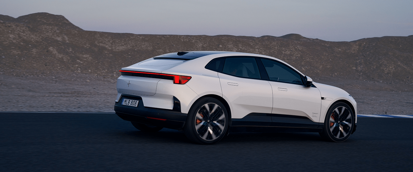 Polestar 4 Coupé driving on a road beside rocky hills at dusk