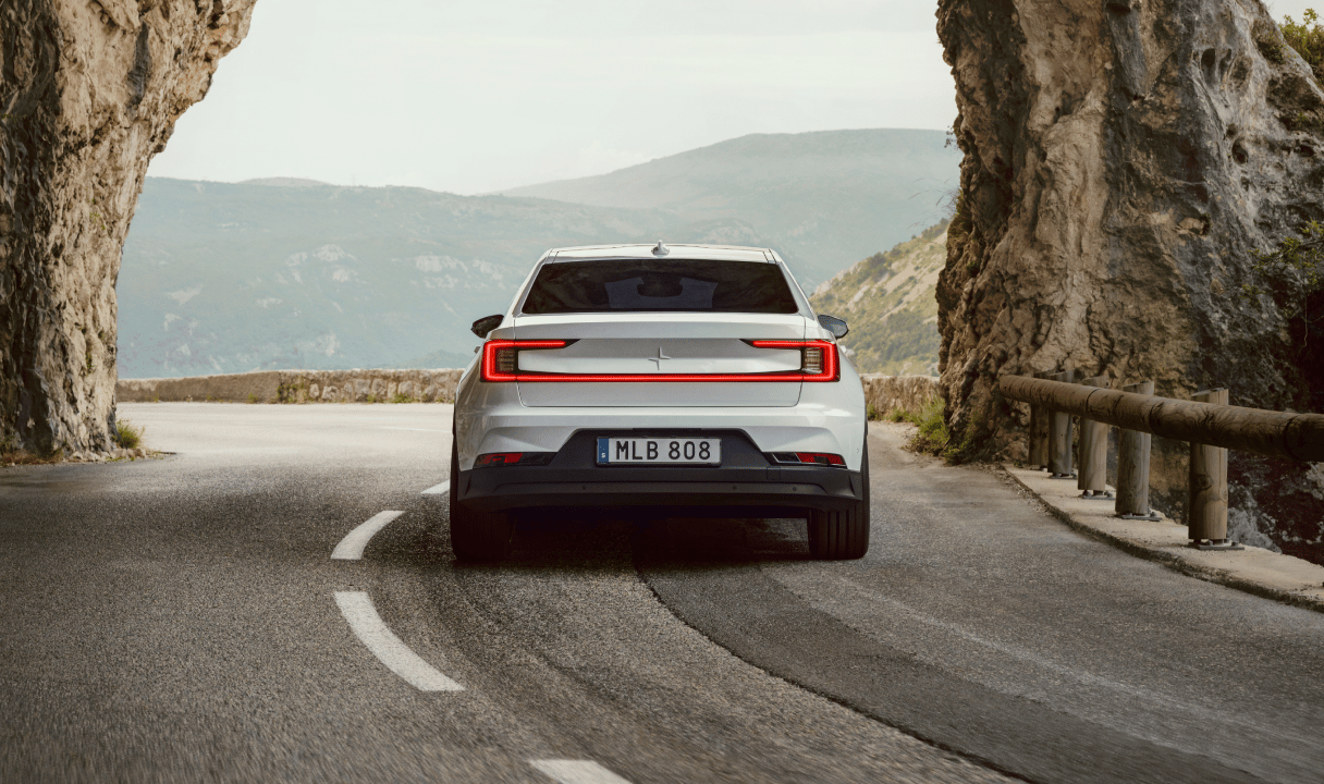 Polestar 2 driving on a mountain road through a rock tunnel