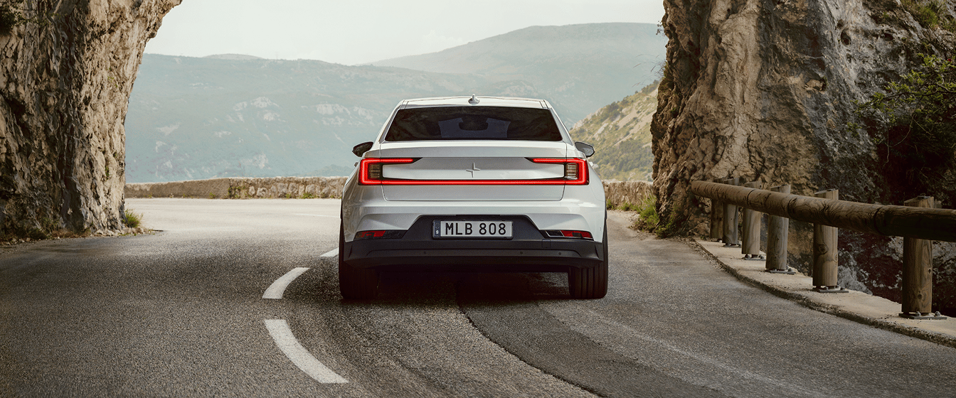 Polestar 2 driving on a mountain road through a rock tunnel