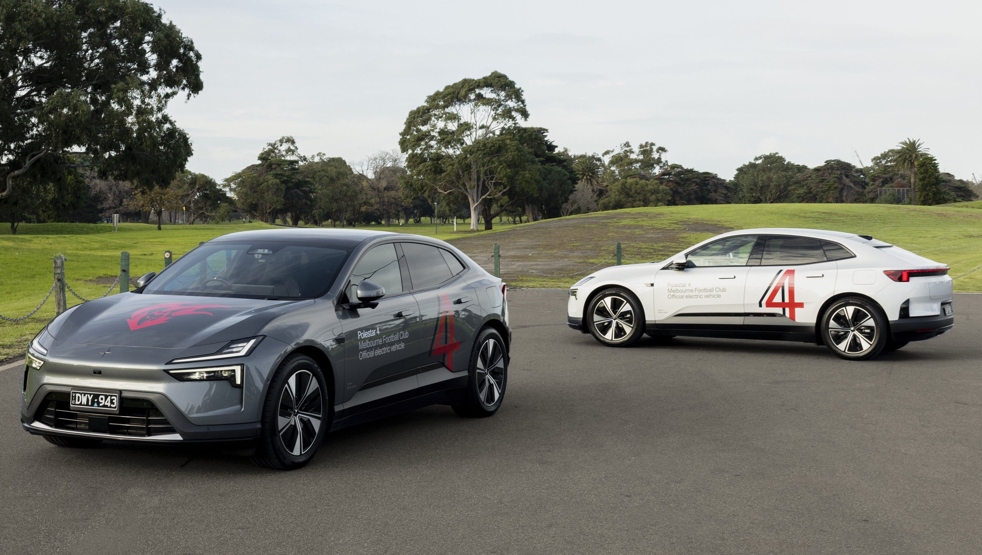 Two Polestar 4 cars shot outside, at opposing 45 degree angles to eachother. One is Storm, the other is Snow. Both have custom livery with number 4 in Melbourne Football Club colours, the club's flamehead emblem on the bonnet, and text on the doors to announce the partnership.
