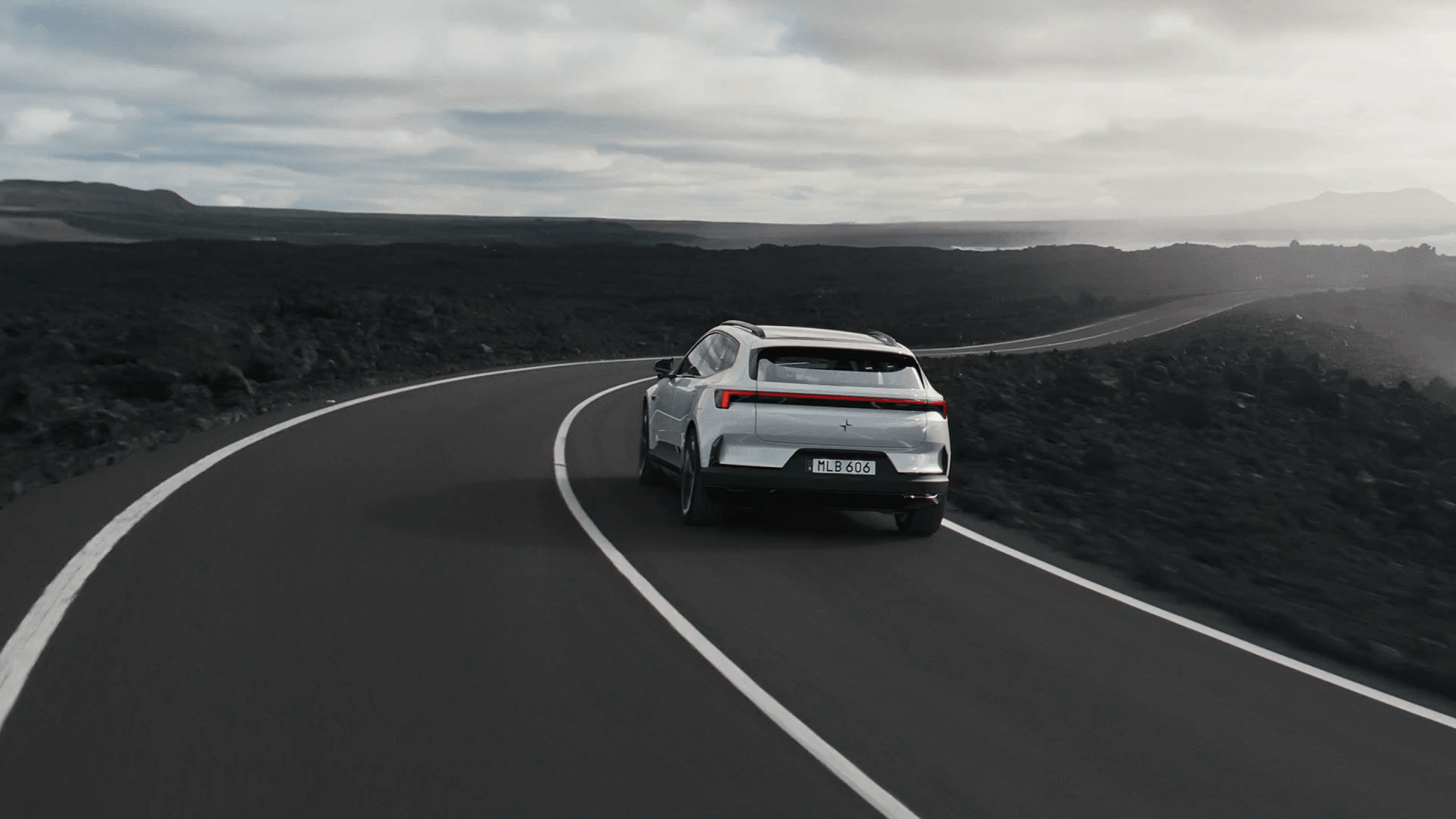 Polestar 4 SUV driving on a highway by the ocean.
