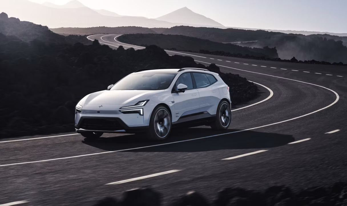 Polestar 4 SUV driving on a winding road through rocky hills